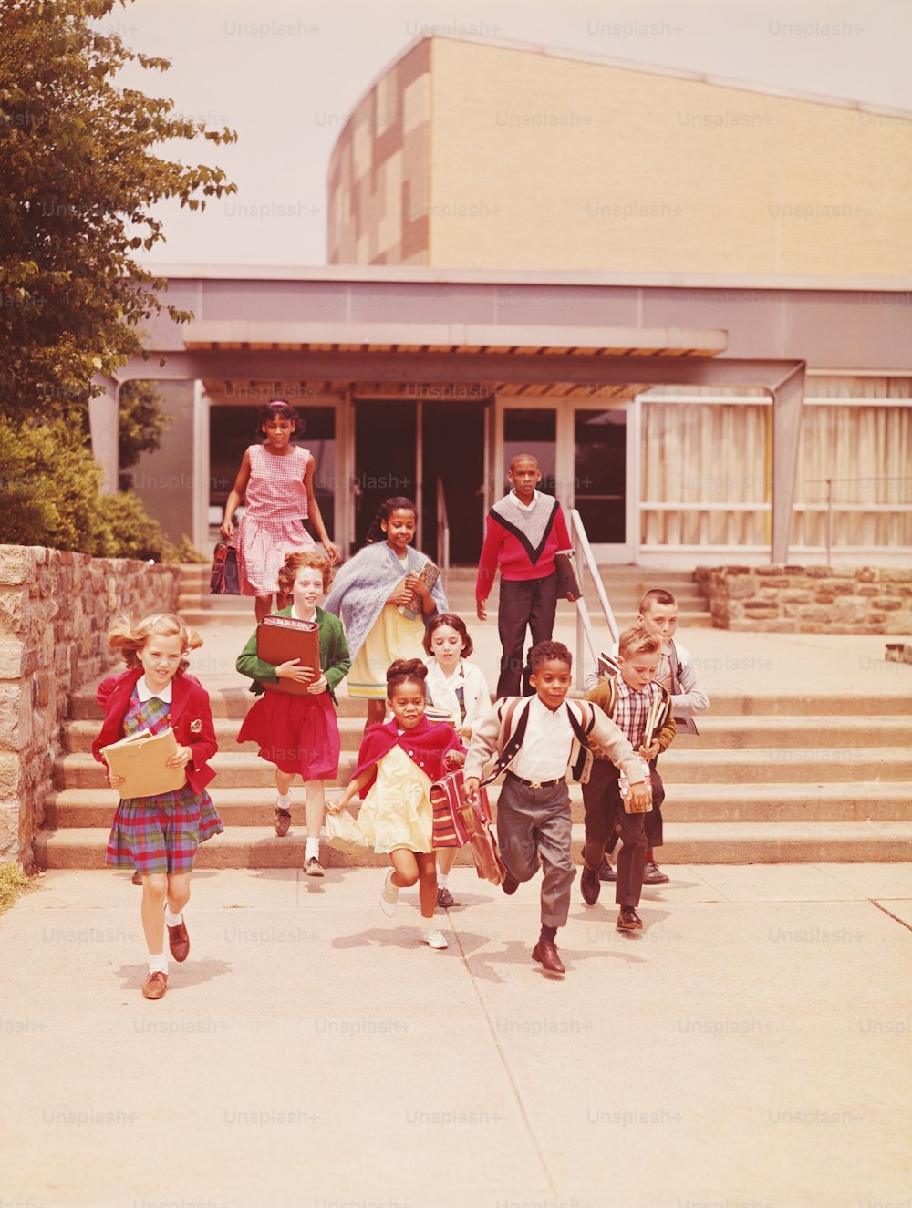 UNITED STATES - CIRCA 1960s:  Children running down steps from elementary school.