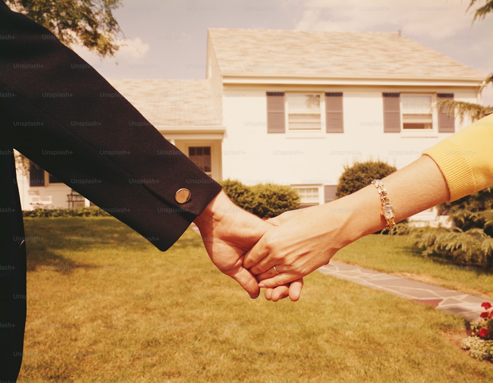 ESTADOS UNIDOS - POR VOLTA DE 1960: Casal de mãos dadas na frente de casa.