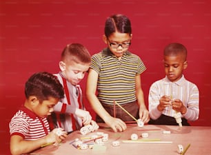 UNITED STATES - CIRCA 1960s:  Four boys playing with tinker toy building set.