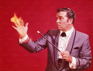 UNITED STATES - CIRCA 1970s:  Magician performing illusion, setting hand on fire with magic wand.