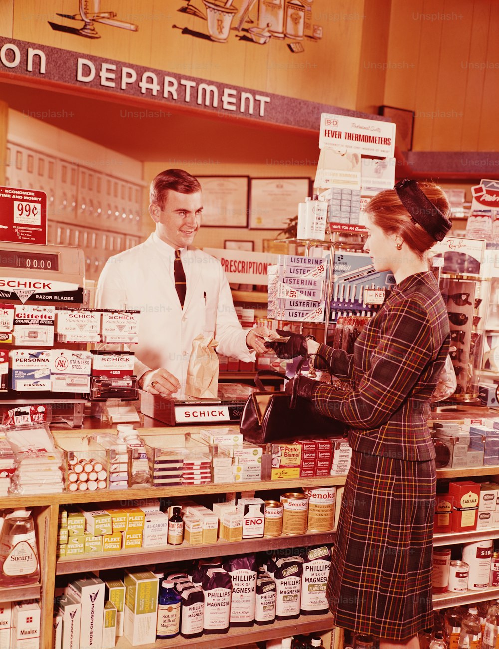 UNITED STATES - CIRCA 1960s:  Woman at pharmacy counter talking to pharmacist.