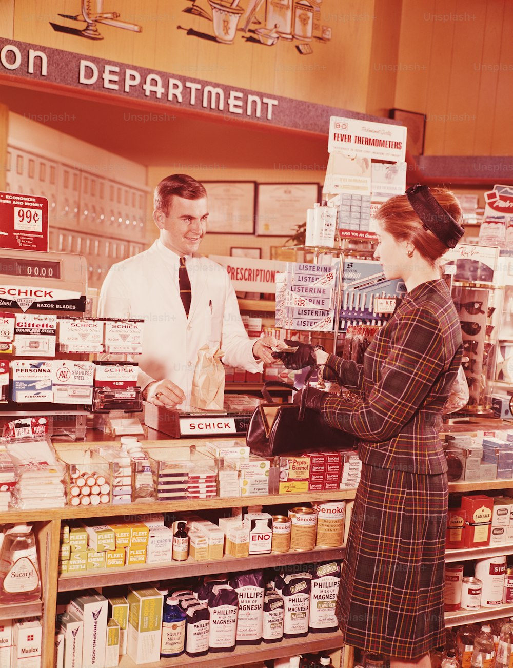 STATI UNITI - 1960 CIRCA: Donna al bancone della farmacia che parla con il farmacista.