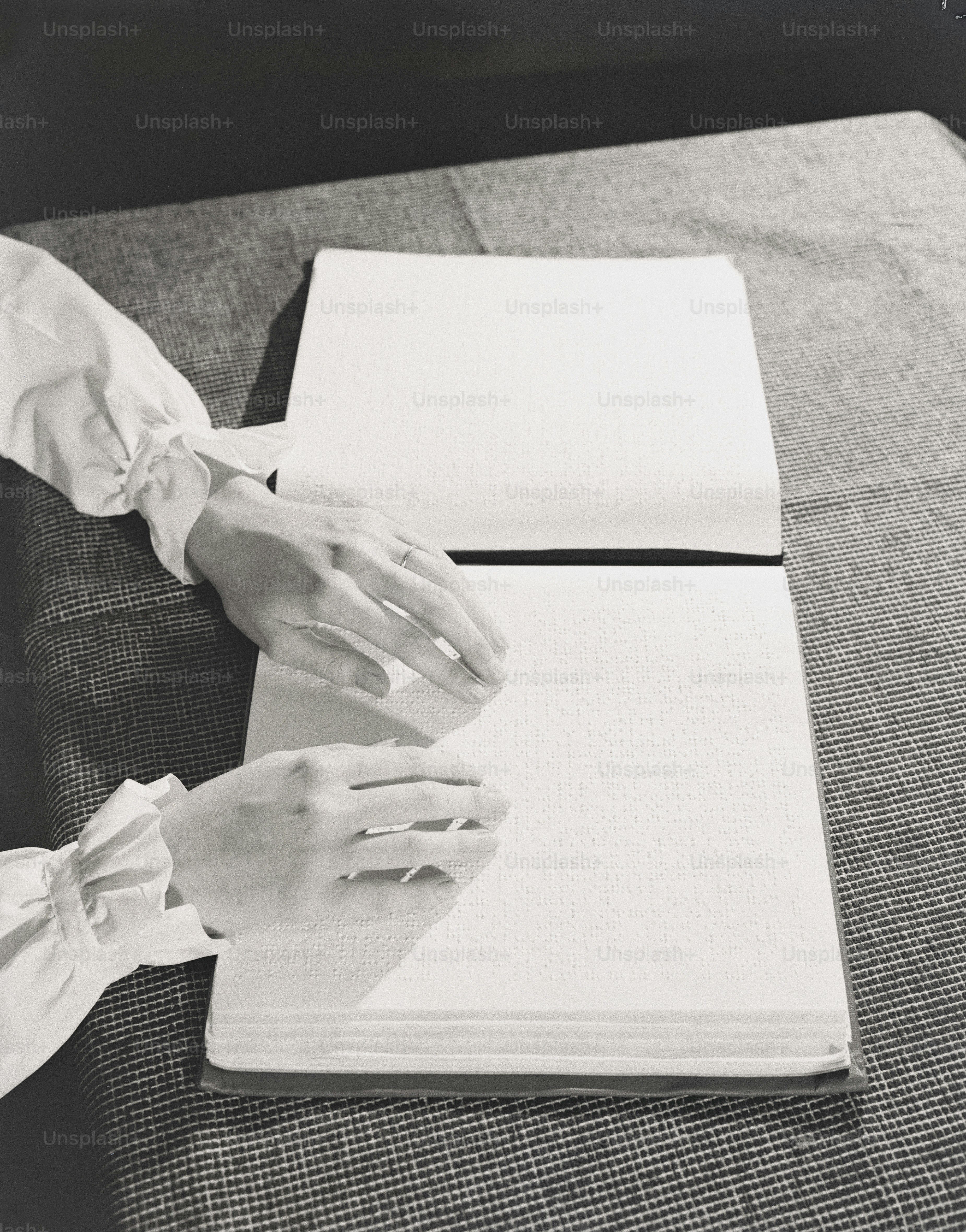 ESTADOS UNIDOS - CIRCA 1940s: Manos de mujer leyendo un libro en braille sobre la mesa.