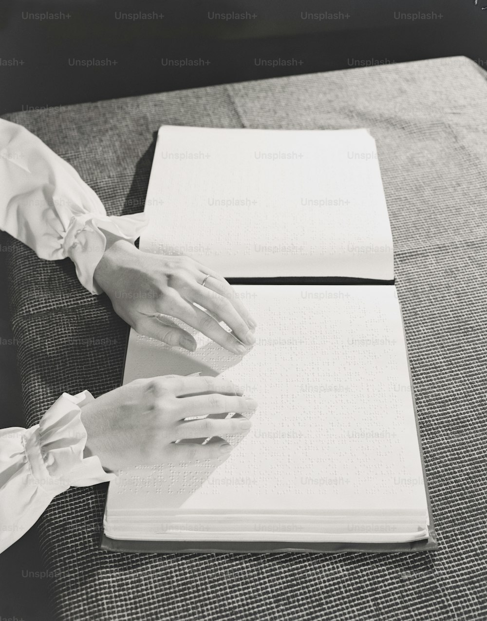 ETATS-UNIS - Circa 1940s : Mains de femme lisant un livre en braille sur une table.
