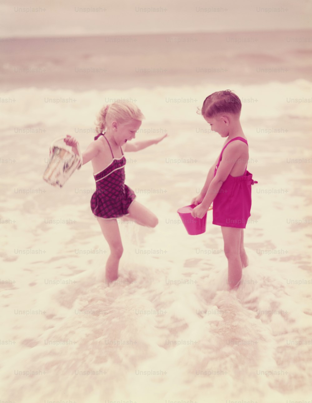 UNITED STATES - CIRCA 1950s:  Boy and girl playing in ocean surf.
