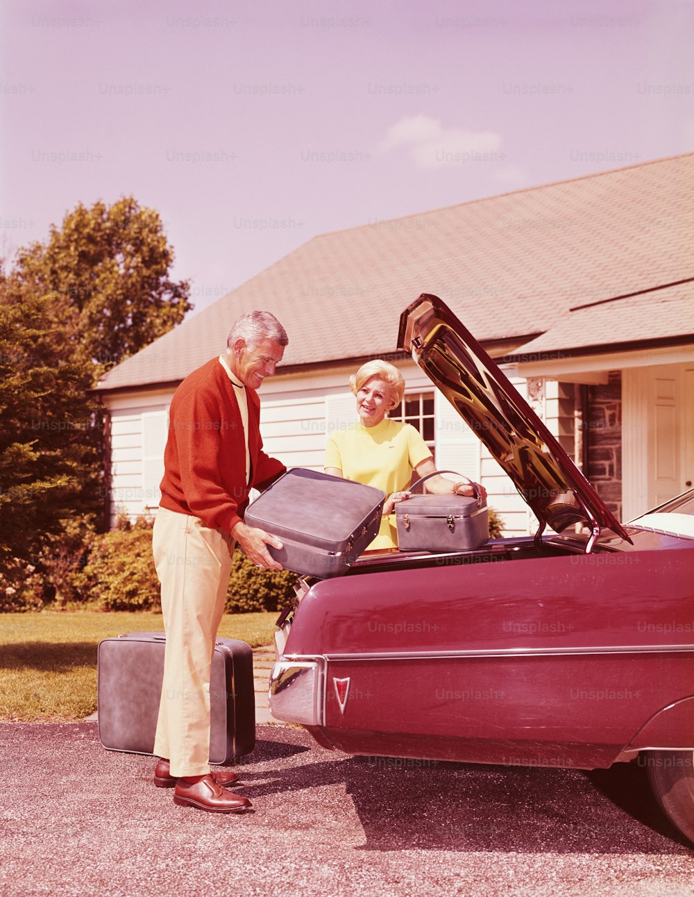 UNITED STATES - CIRCA 1960s:  Mature couple loading bags into car.