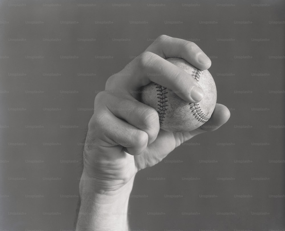 ESTADOS UNIDOS - POR VOLTA DE 1930: A mão do homem segurando o beisebol em forma de arremesso.