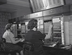 ESTADOS UNIDOS - CIRCA 1950s: Dos mujeres con auriculares, trabajando en la centralita telefónica.
