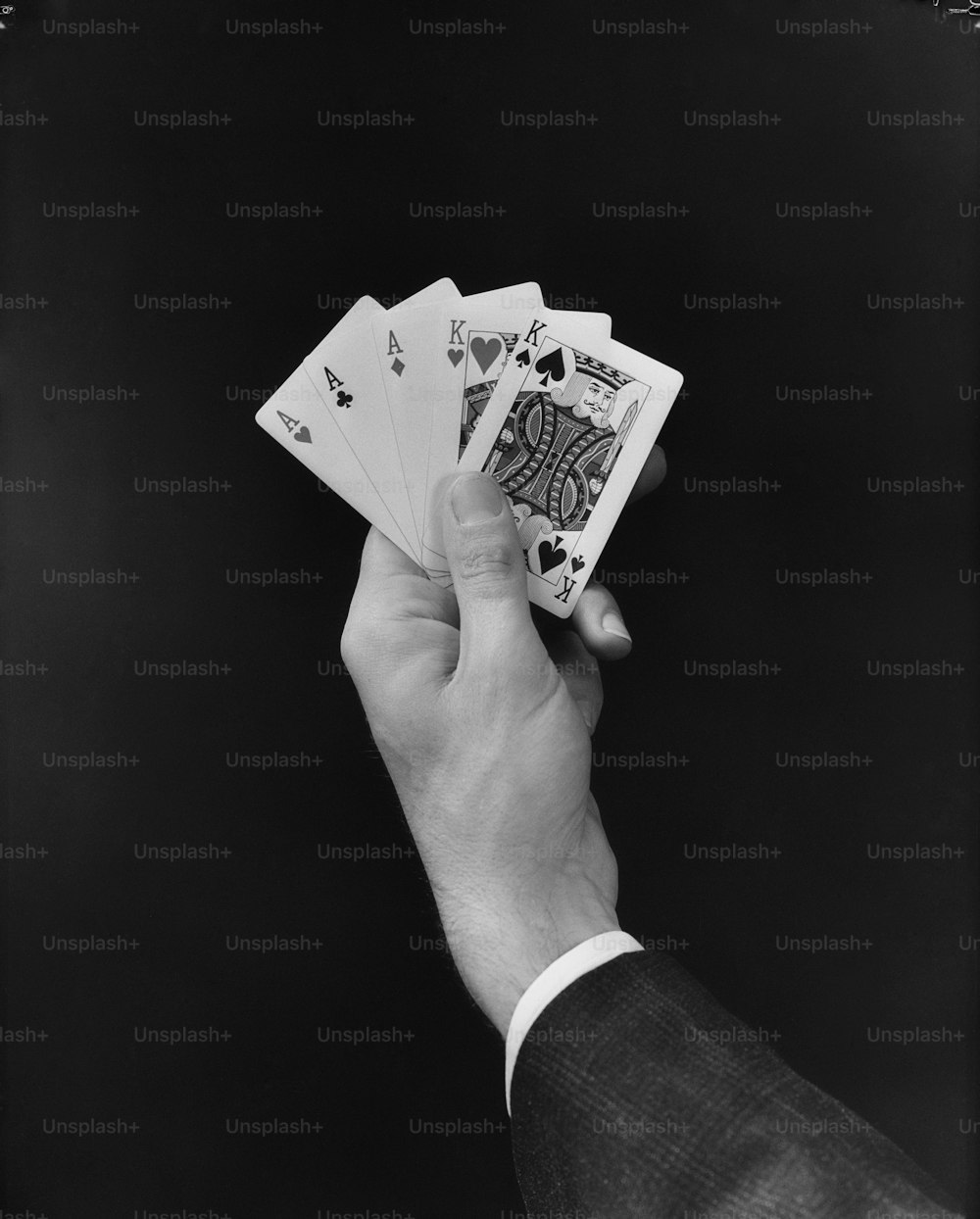 ESTADOS UNIDOS - CIRCA 1950s: La mano de un hombre sosteniendo una mano de cartas de póquer 'fullhouse'.