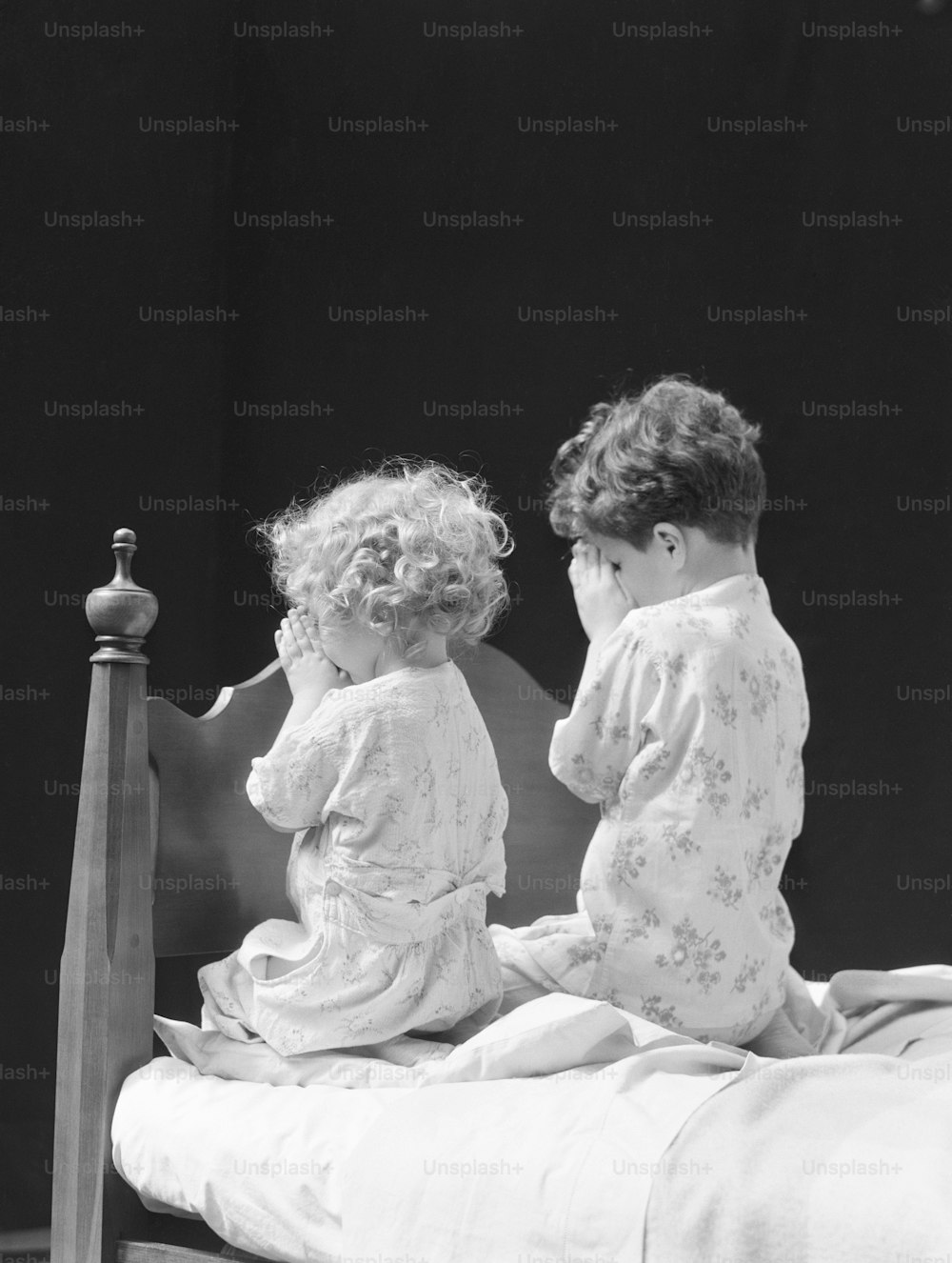 미국 - 1930년대경: 침대 옆에 무릎을 꿇고 기도하는 소년과 소녀, 뒷모습.