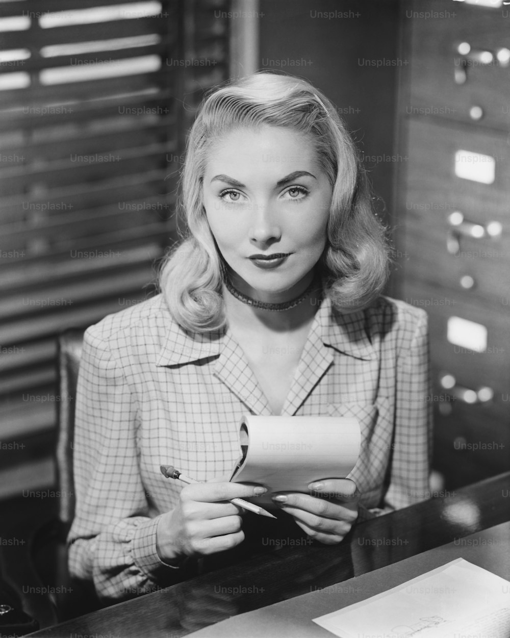 une femme assise à un bureau tenant un morceau de papier