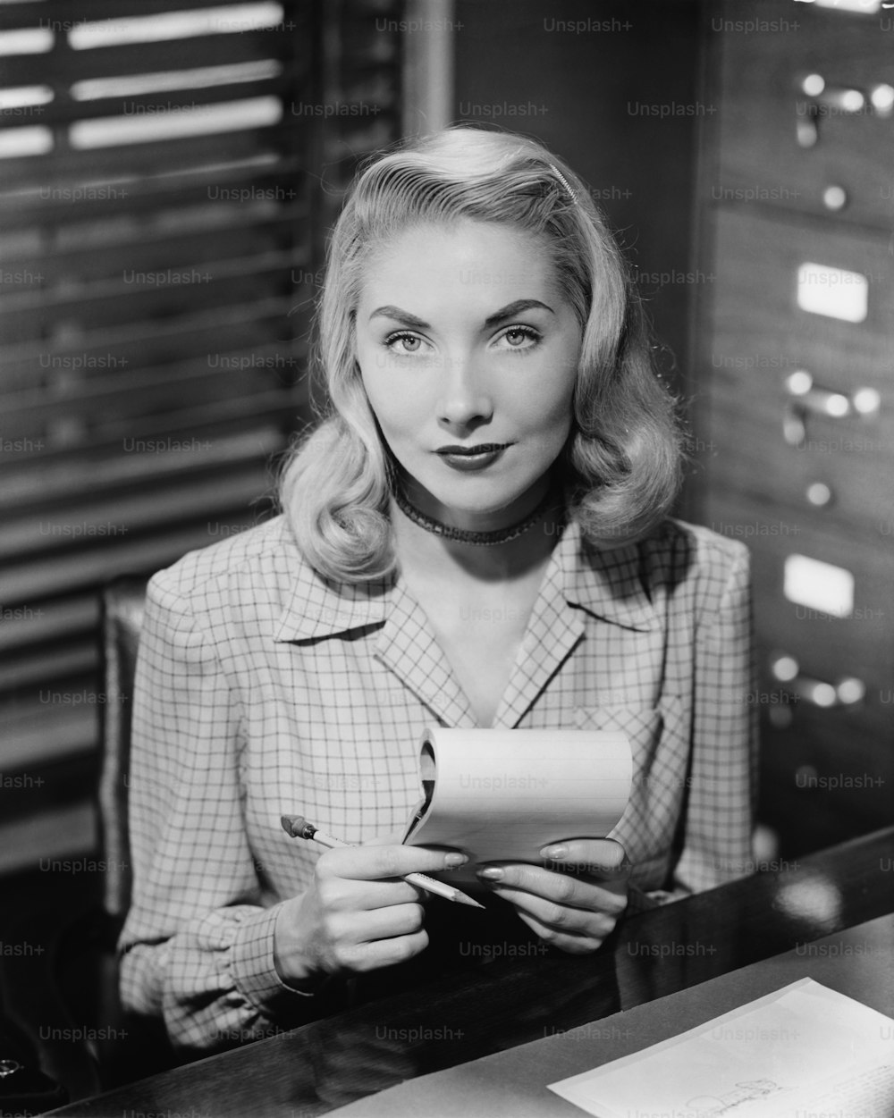 a woman sitting at a desk holding a piece of paper