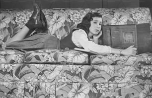 a woman laying on top of a floral couch
