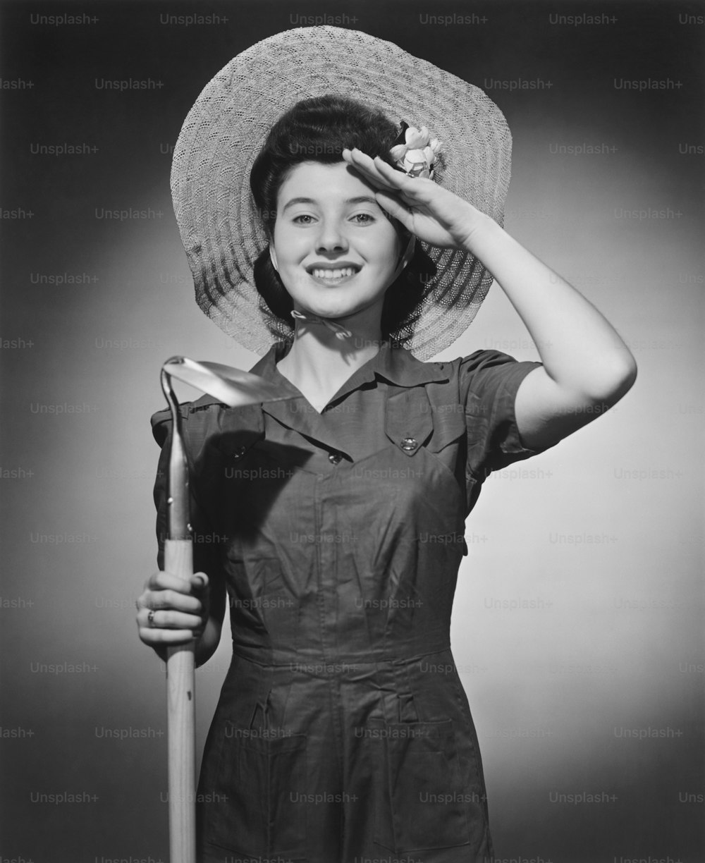 a woman wearing a hat and holding a shovel