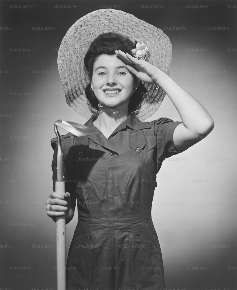 una mujer con sombrero y sosteniendo una pala