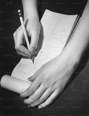 a person writing on a piece of paper with a pencil
