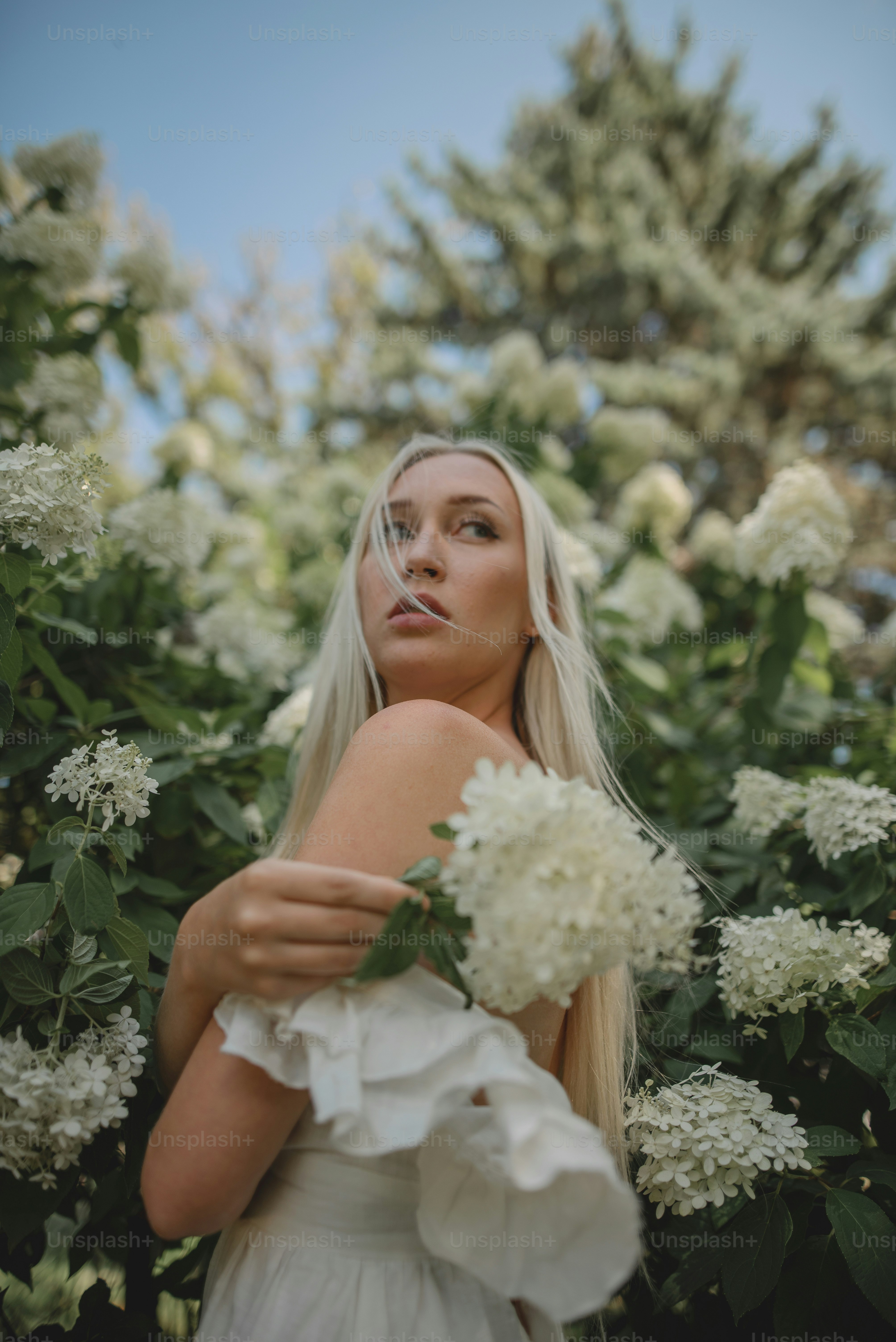 Une femme en robe blanche tenant un bouquet de fleurs