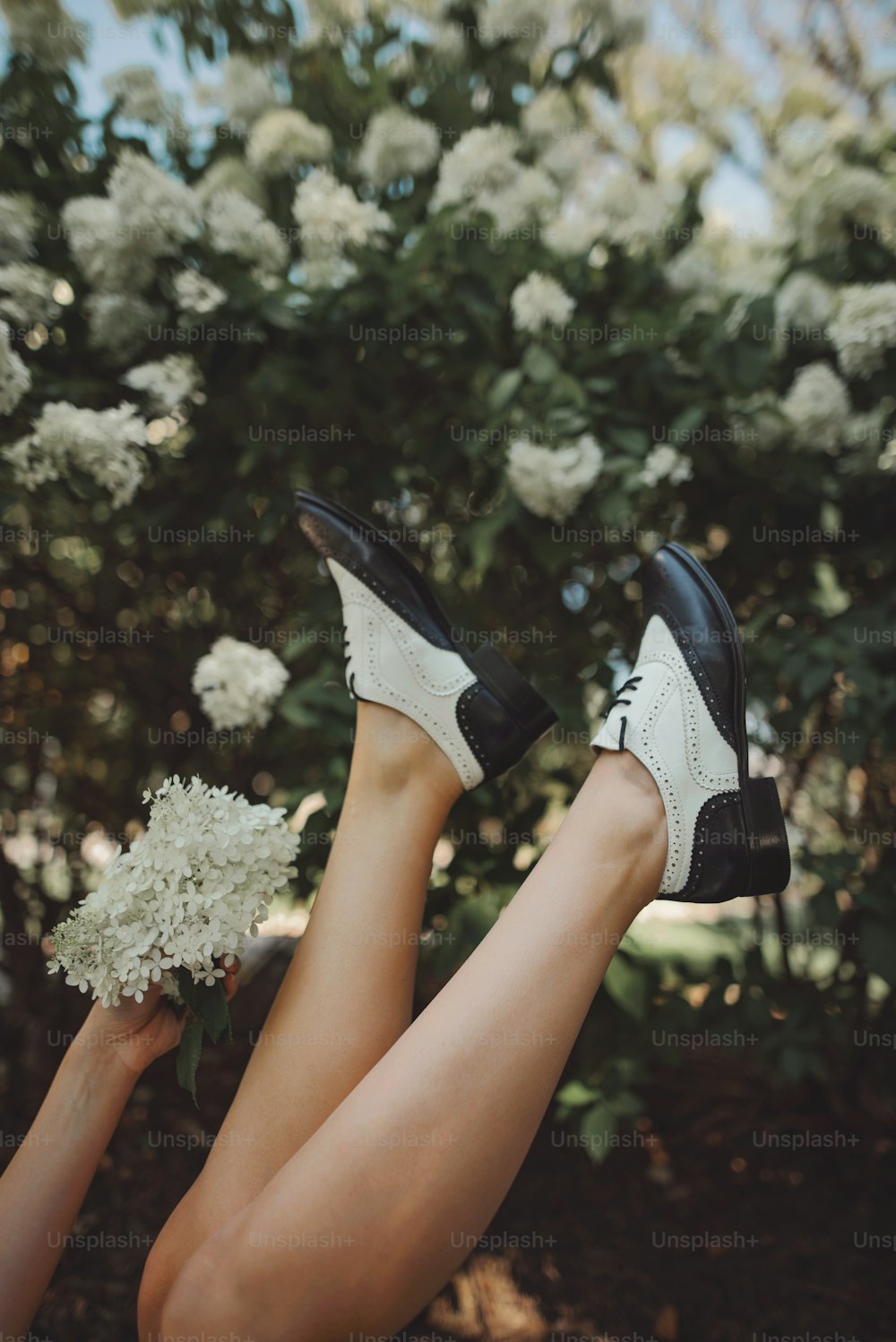 a woman's legs with black and white shoes and flowers