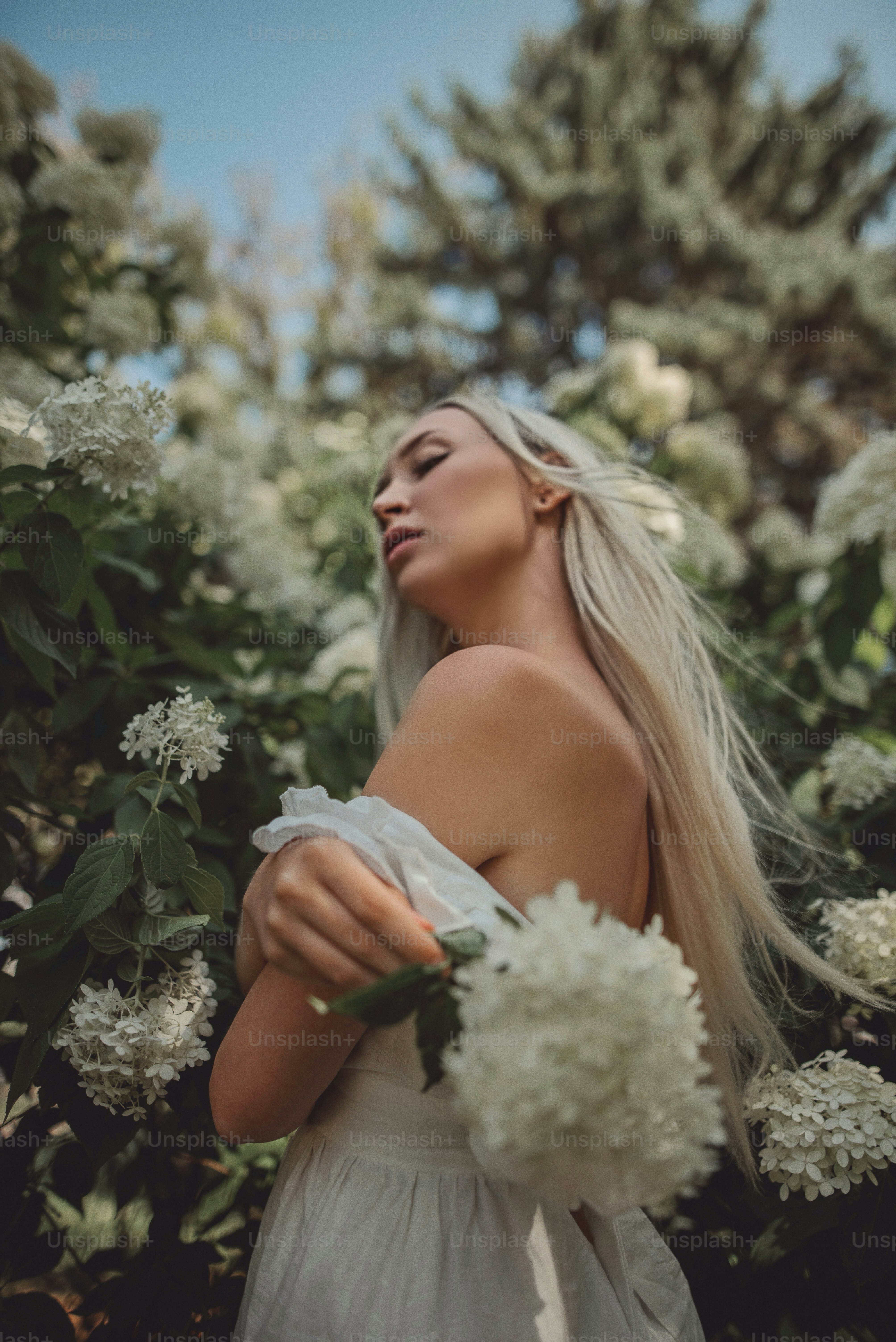 Une femme en robe blanche tenant un bouquet de fleurs