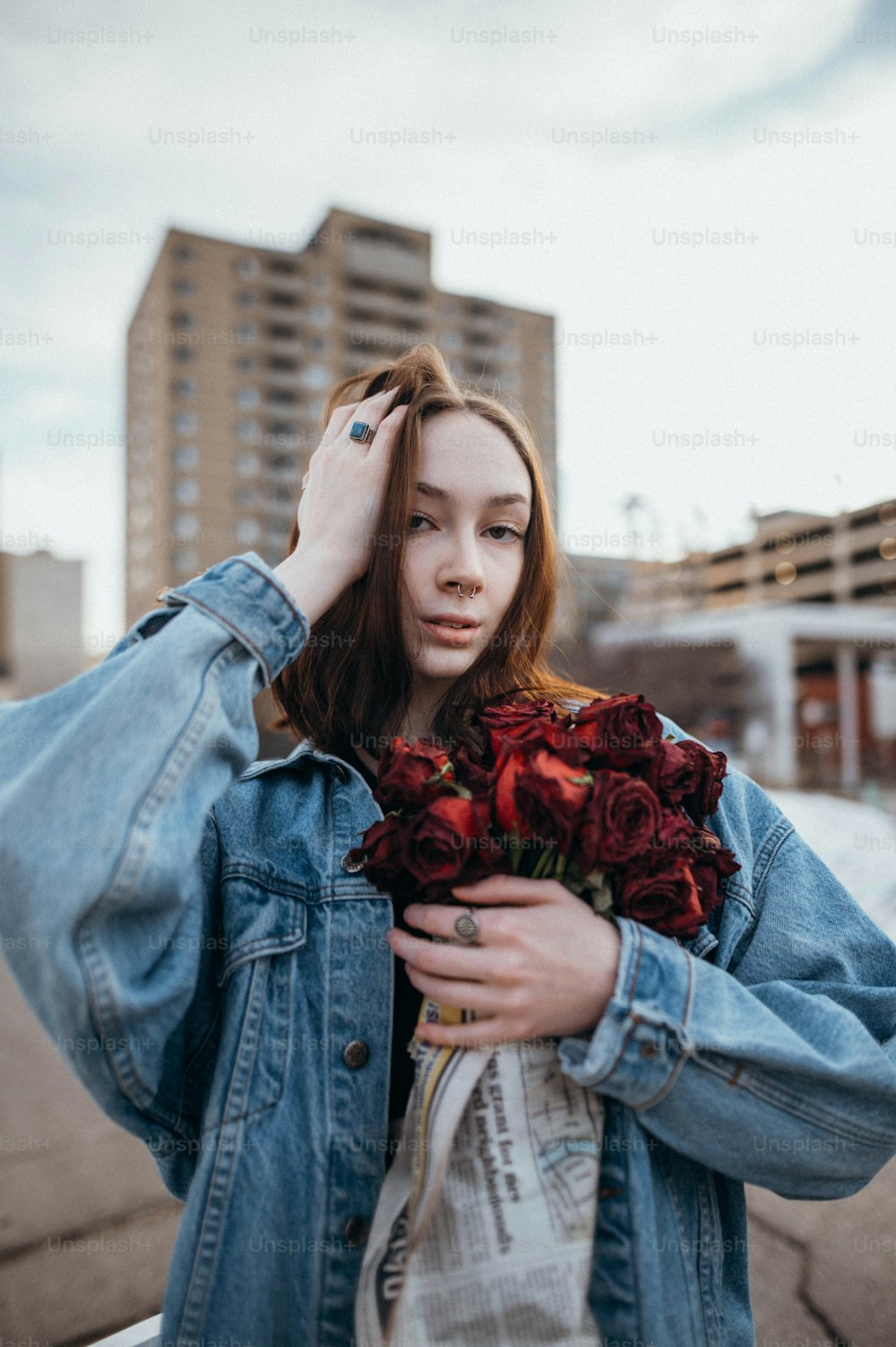 Eine Frau in einer Jeansjacke hält einen Rosenstrauß in der Hand