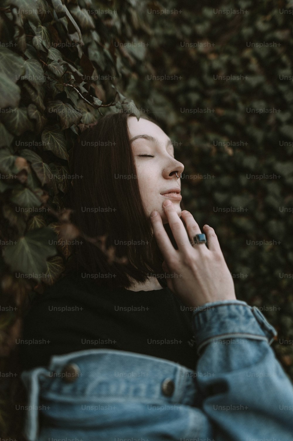 a woman with her eyes closed leaning against a tree