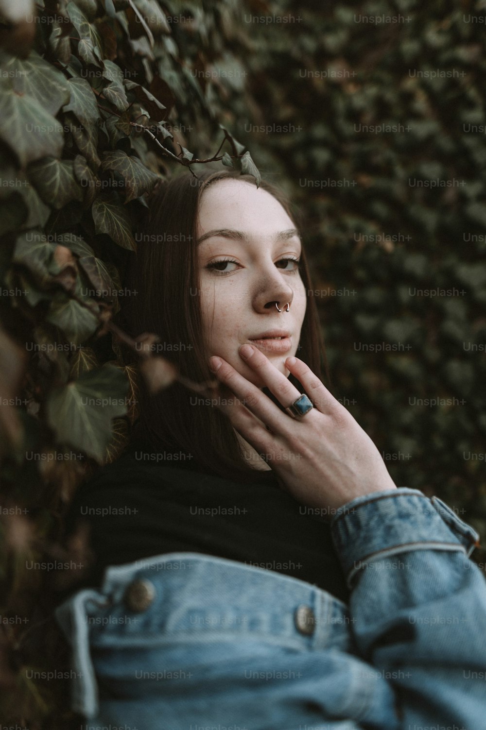 Eine Frau, die sich mit der Hand auf dem Mund an einen Baum lehnt