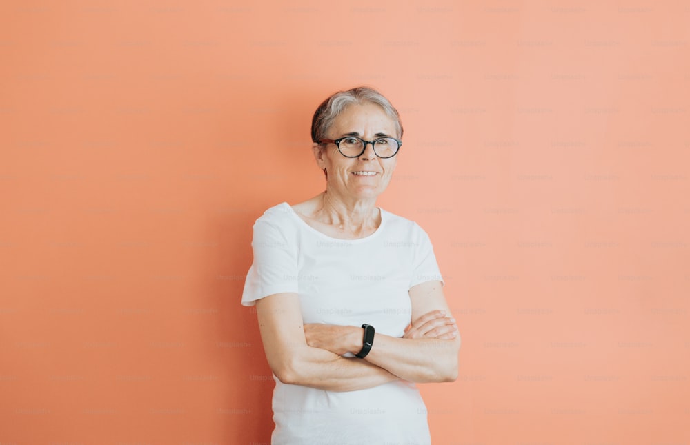Una donna anziana che indossa gli occhiali in piedi con le braccia incrociate