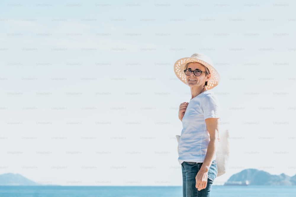 Une femme debout sur une plage portant un chapeau