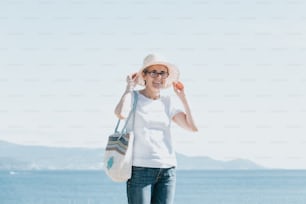 a woman standing on a beach holding a purse