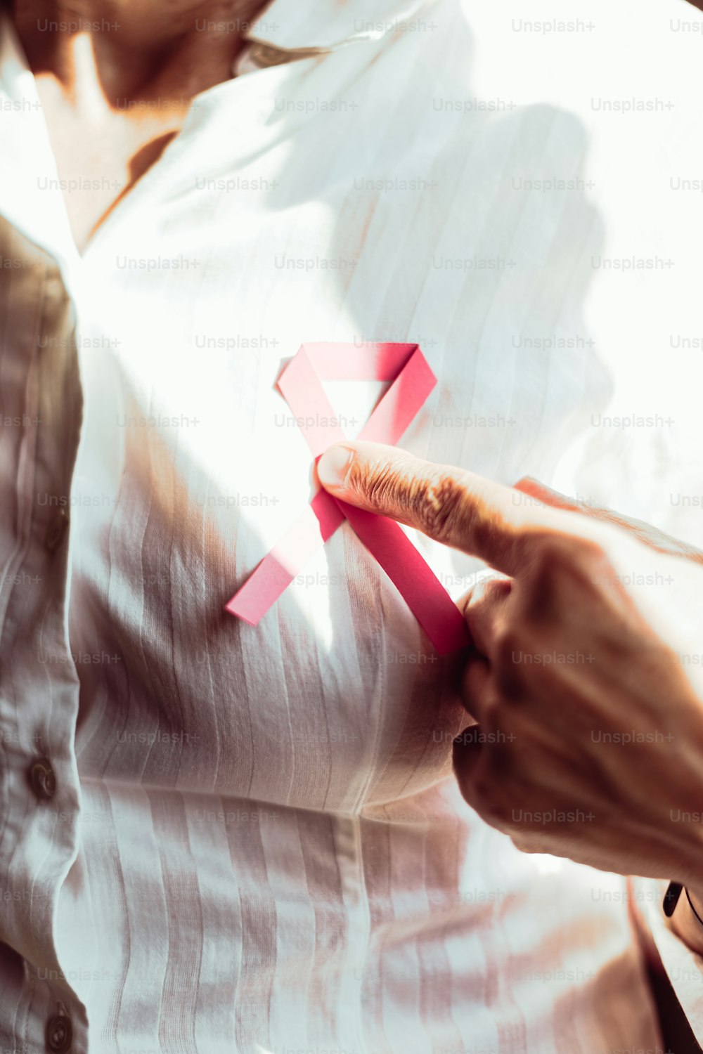 a woman holding a pink ribbon with a pink cross on it