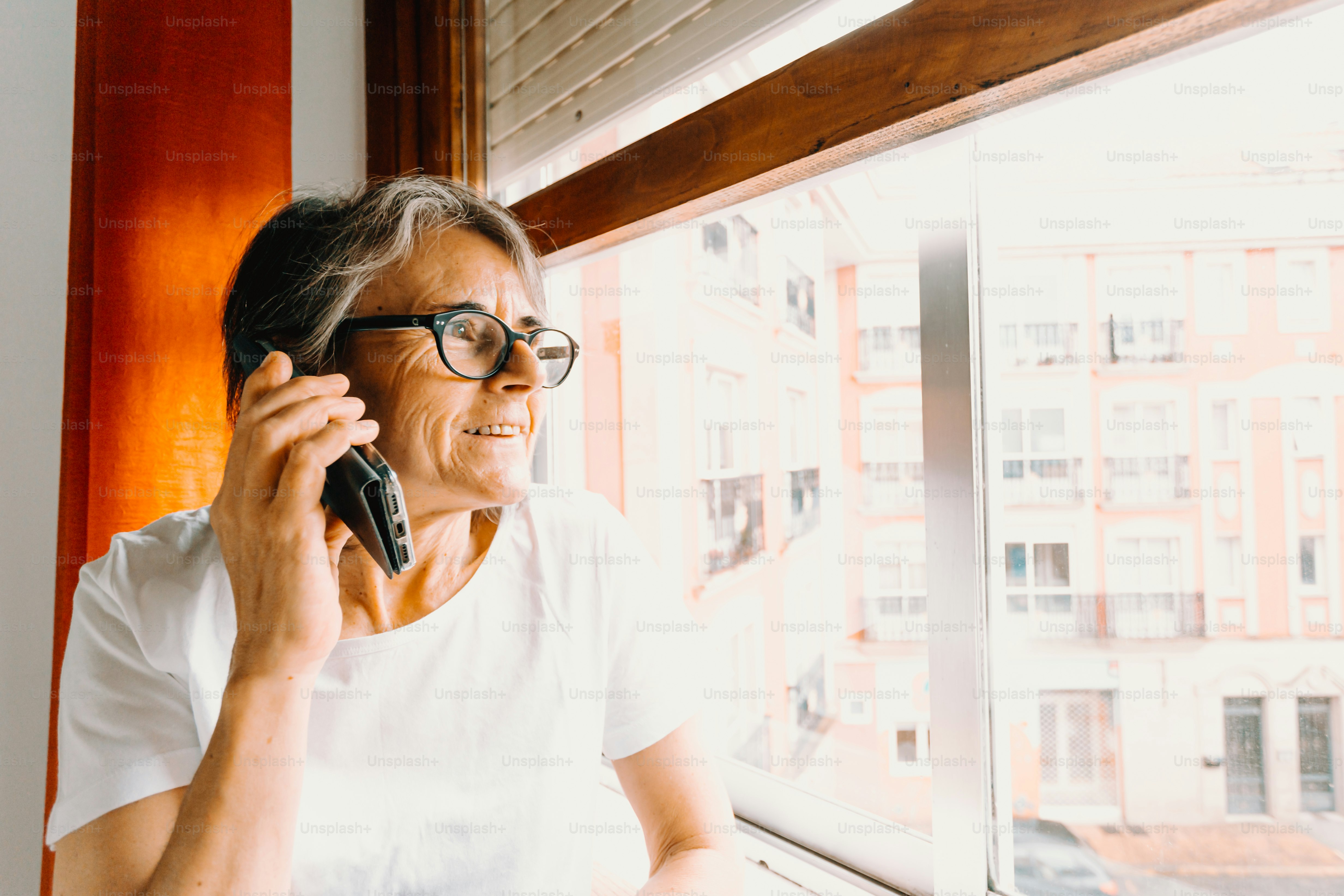 a woman talking on a cell phone next to a window