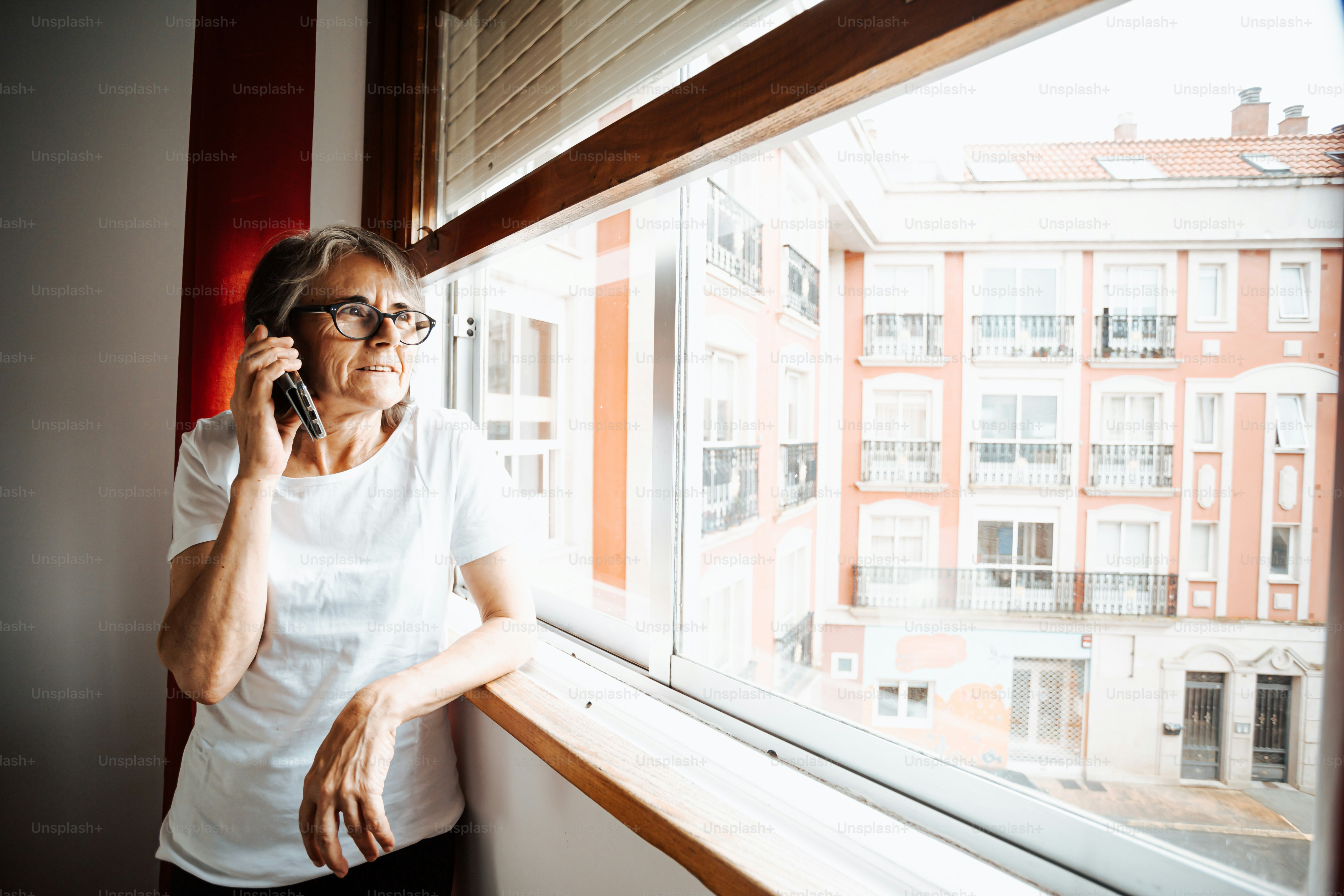 a woman is talking on a cell phone by a window