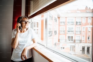uma mulher está falando em um celular perto de uma janela