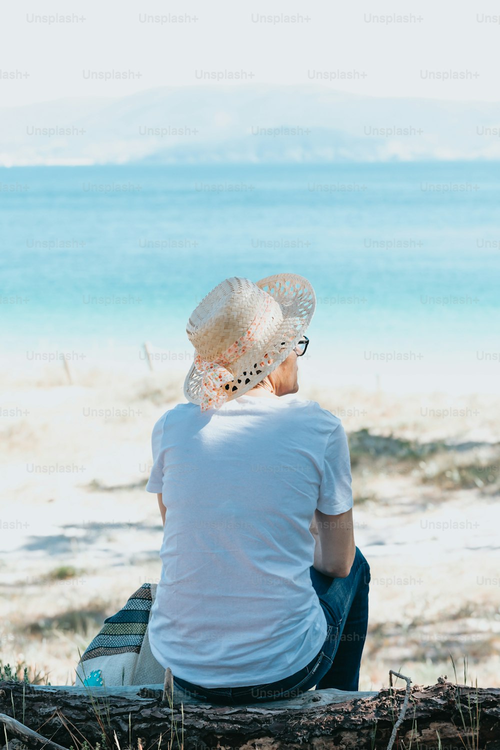 uma mulher sentada em um tronco na praia