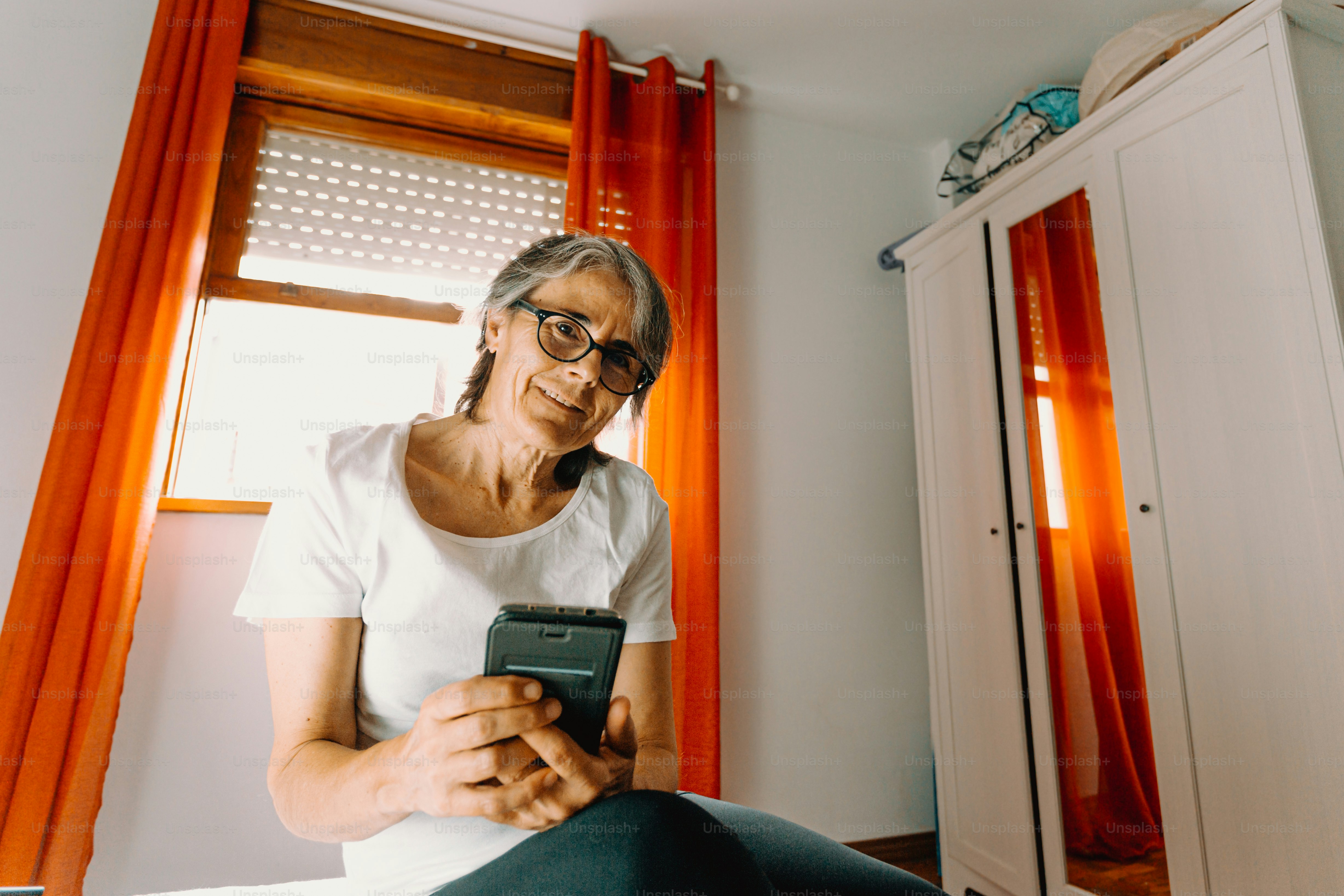 Eine Frau, die auf einem Bett sitzt und auf ihr Handy schaut