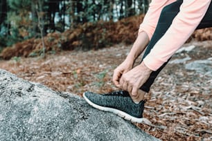 a person tying a shoelace on top of a rock