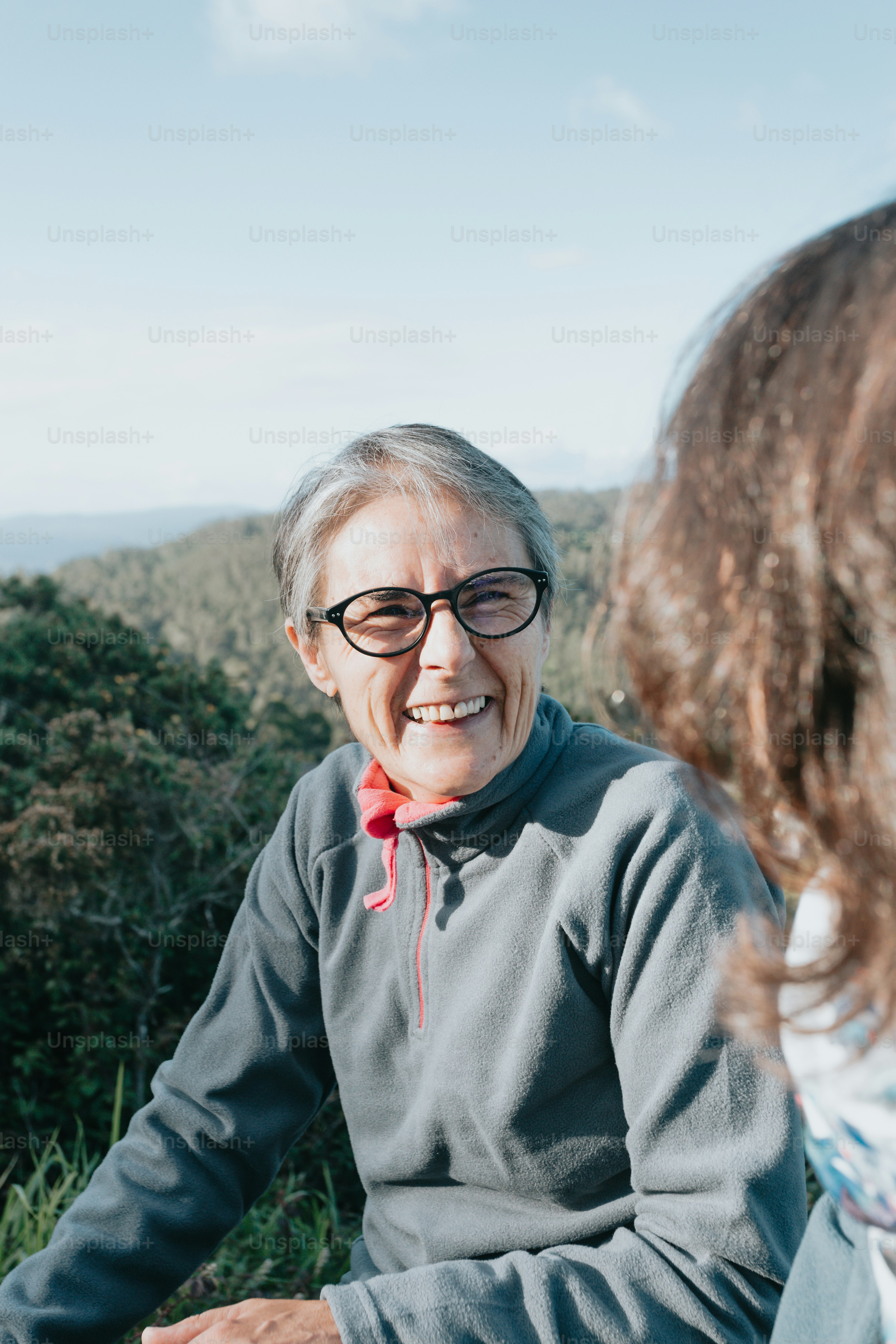 Una mujer sentada junto a un hombre en la cima de una exuberante ladera verde
