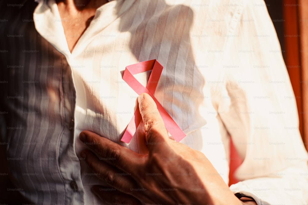 a man holding a pink ribbon in his hands