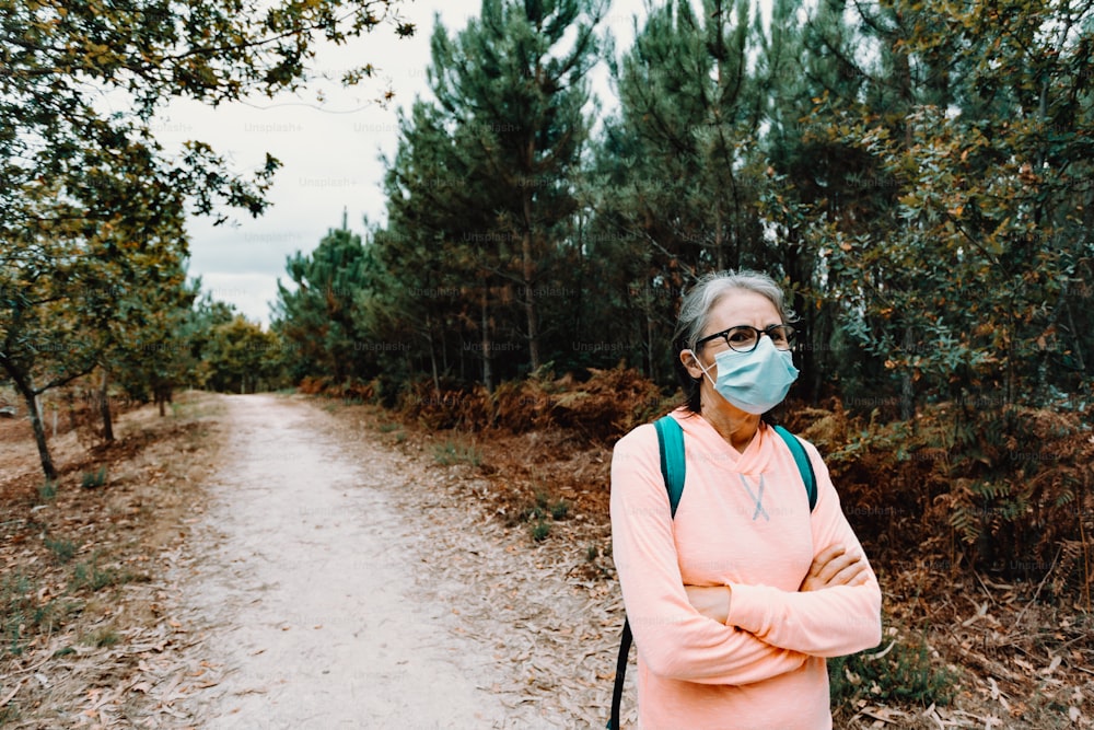 uma mulher usando uma máscara facial em pé em uma estrada de terra