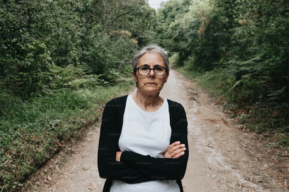 a woman standing on a dirt road in the woods