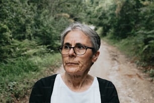 a woman with glasses standing on a dirt road