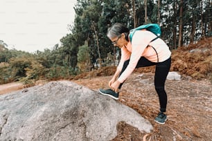 a woman in a pink shirt and black pants standing on a rock