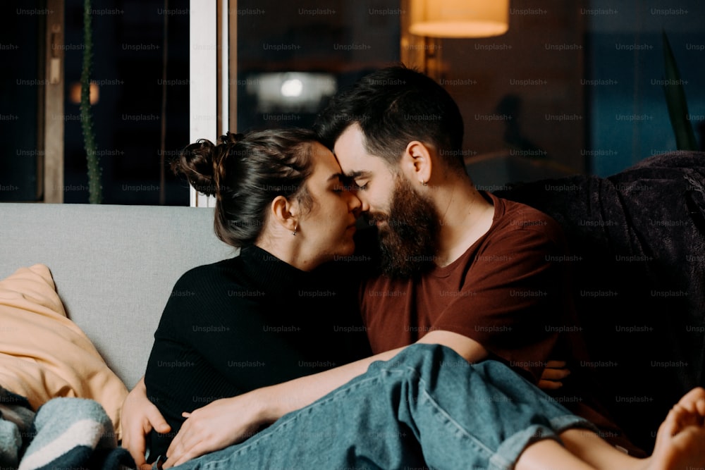 a man and woman sitting on a couch kissing