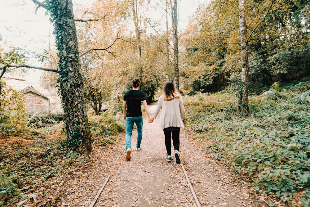 a man and a woman walking down a path in the woods