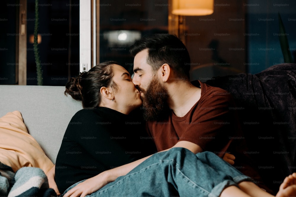 a man and a woman sitting on a couch kissing