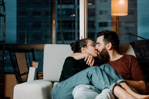 um homem e uma mulher sentados em um sofá se beijando