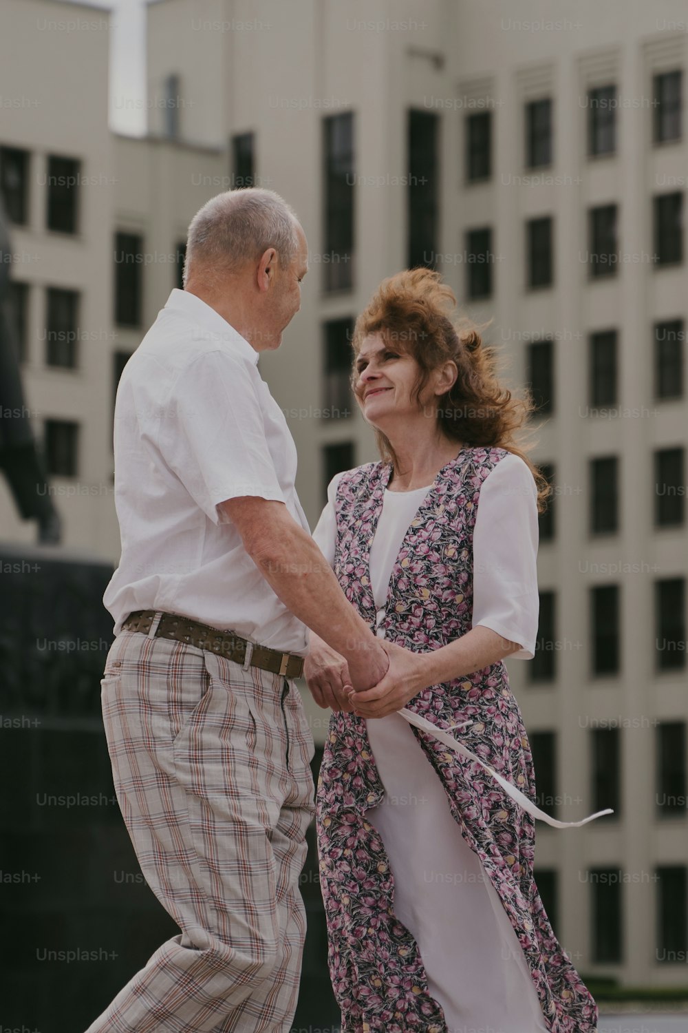a man and a woman holding hands in front of a building