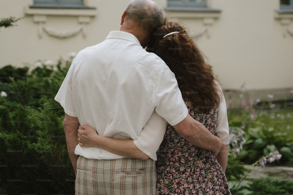 um homem e uma mulher abraçados em frente a uma casa