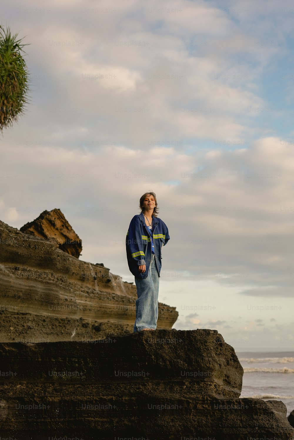 a man standing on top of a rock near the ocean