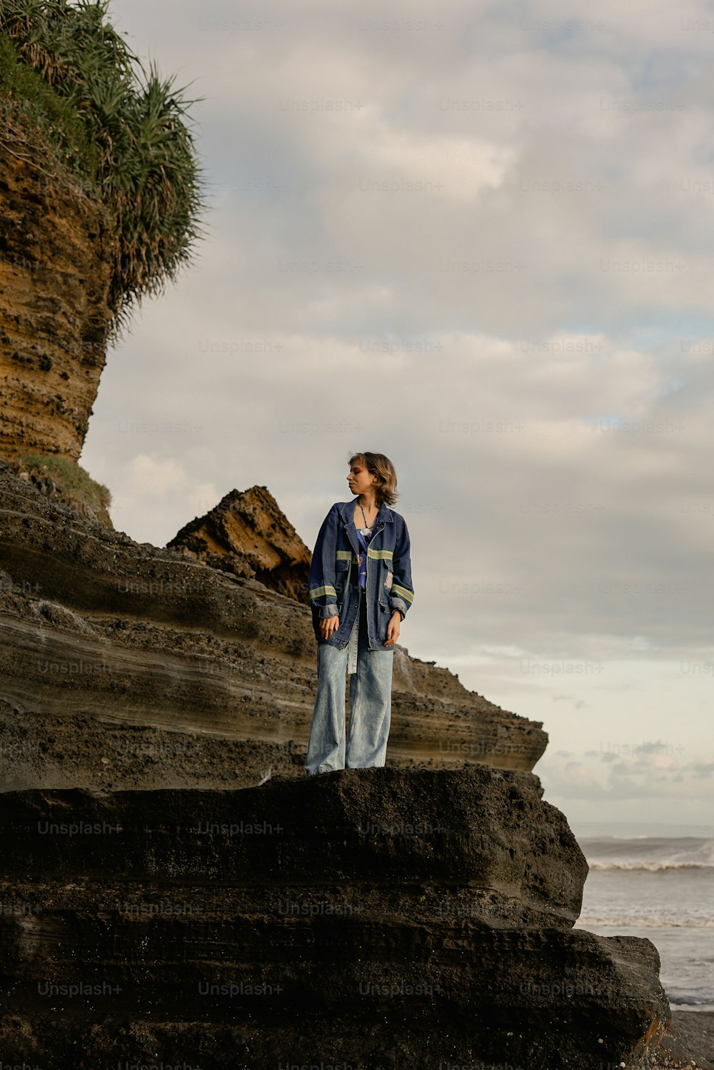 Eine Frau, die auf einem Felsen in der Nähe des Ozeans steht